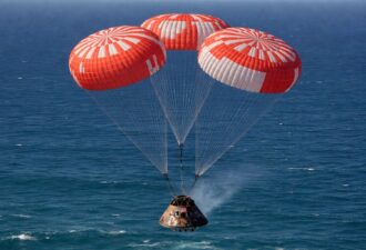 Космічна капсула Orion спускається на парашутах над океаном після повернення з місії до Місяця.