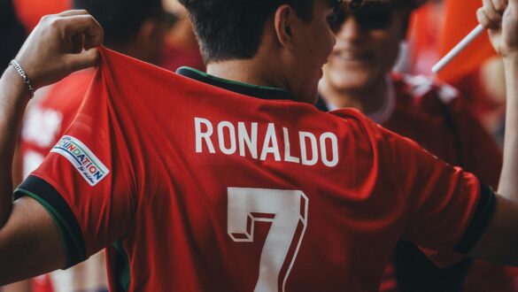 Вболівальник у червоній футболці збірної Португалії з написом «Ronaldo» і номером 7 на спині, тримає її руками серед натовпу.